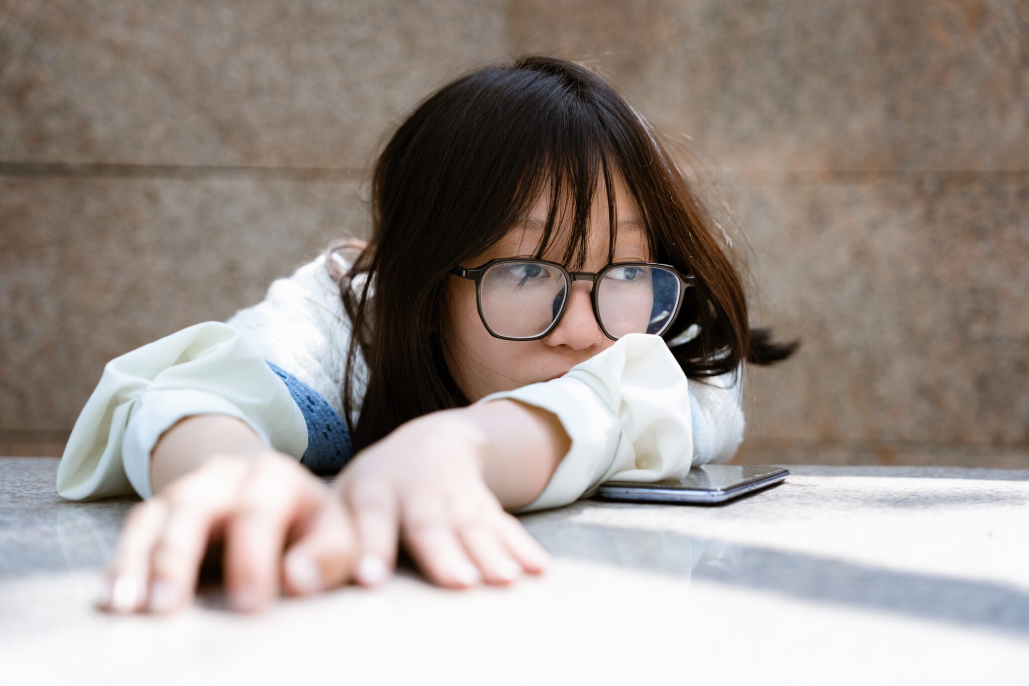 Sad woman lays her arms and hands on a white table