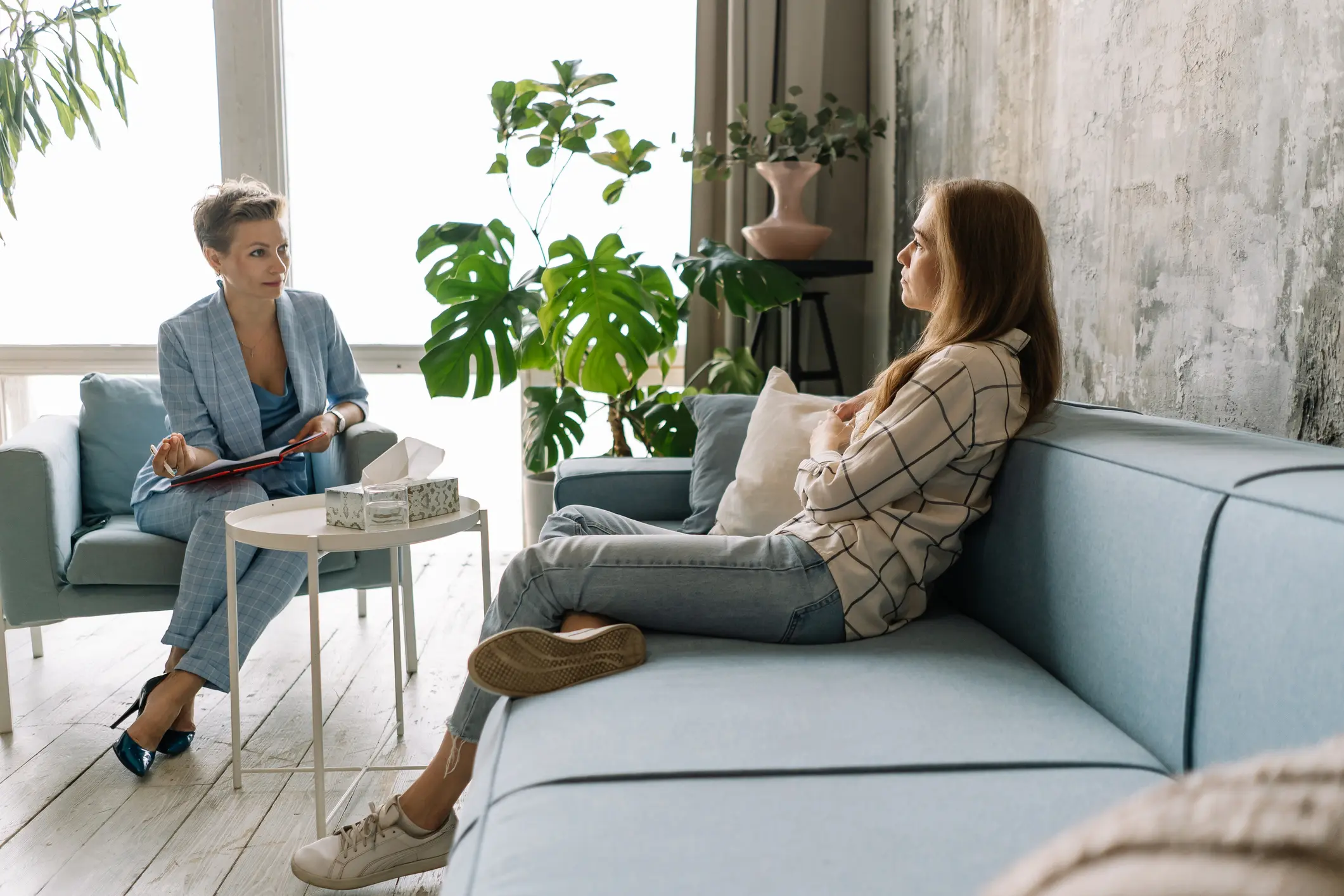 Sad woman leans back on the sofa while speaking to her therapist