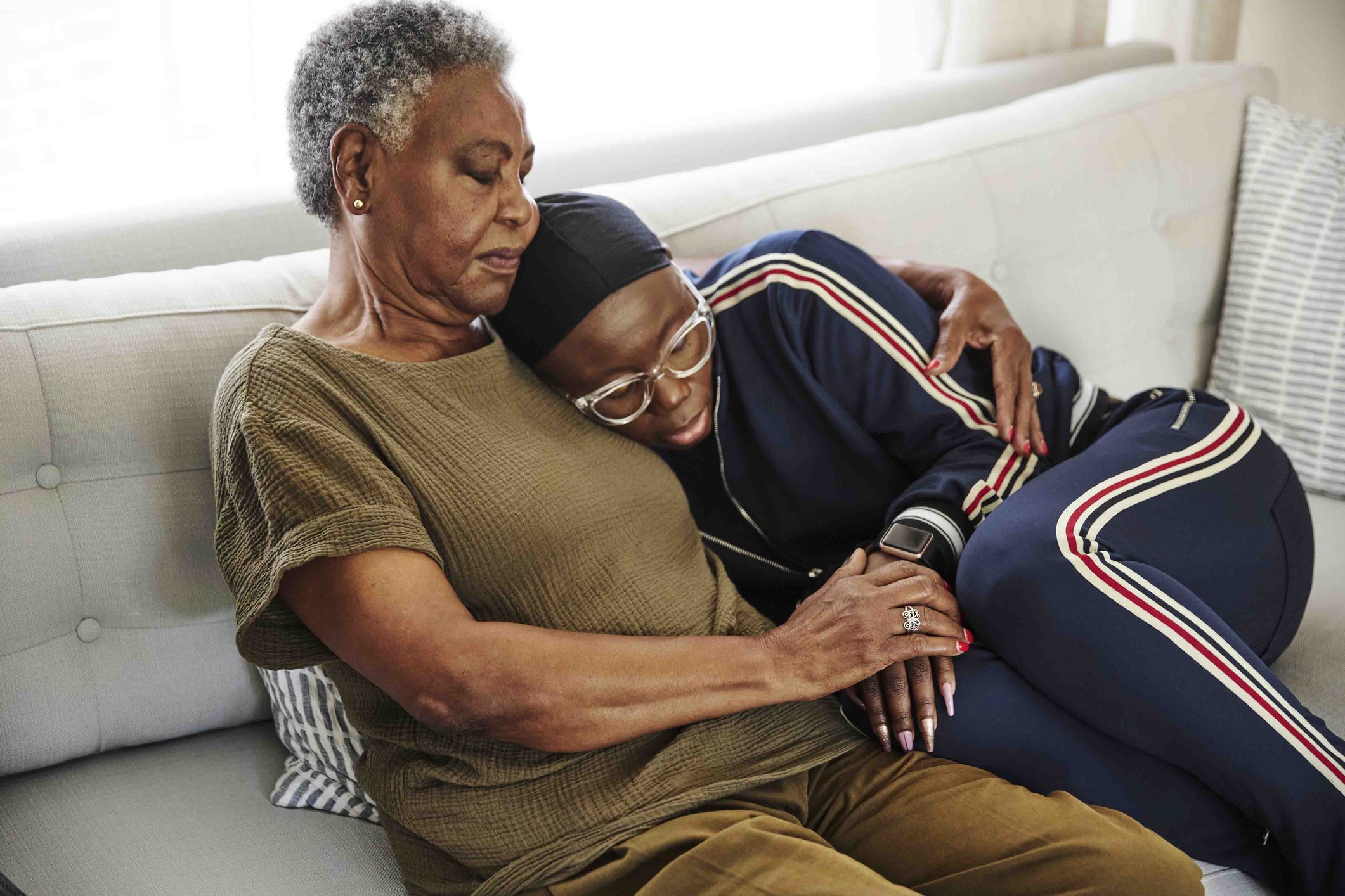 An elderly woman hugs and comforts her adult child who struggles with agoraphobia.